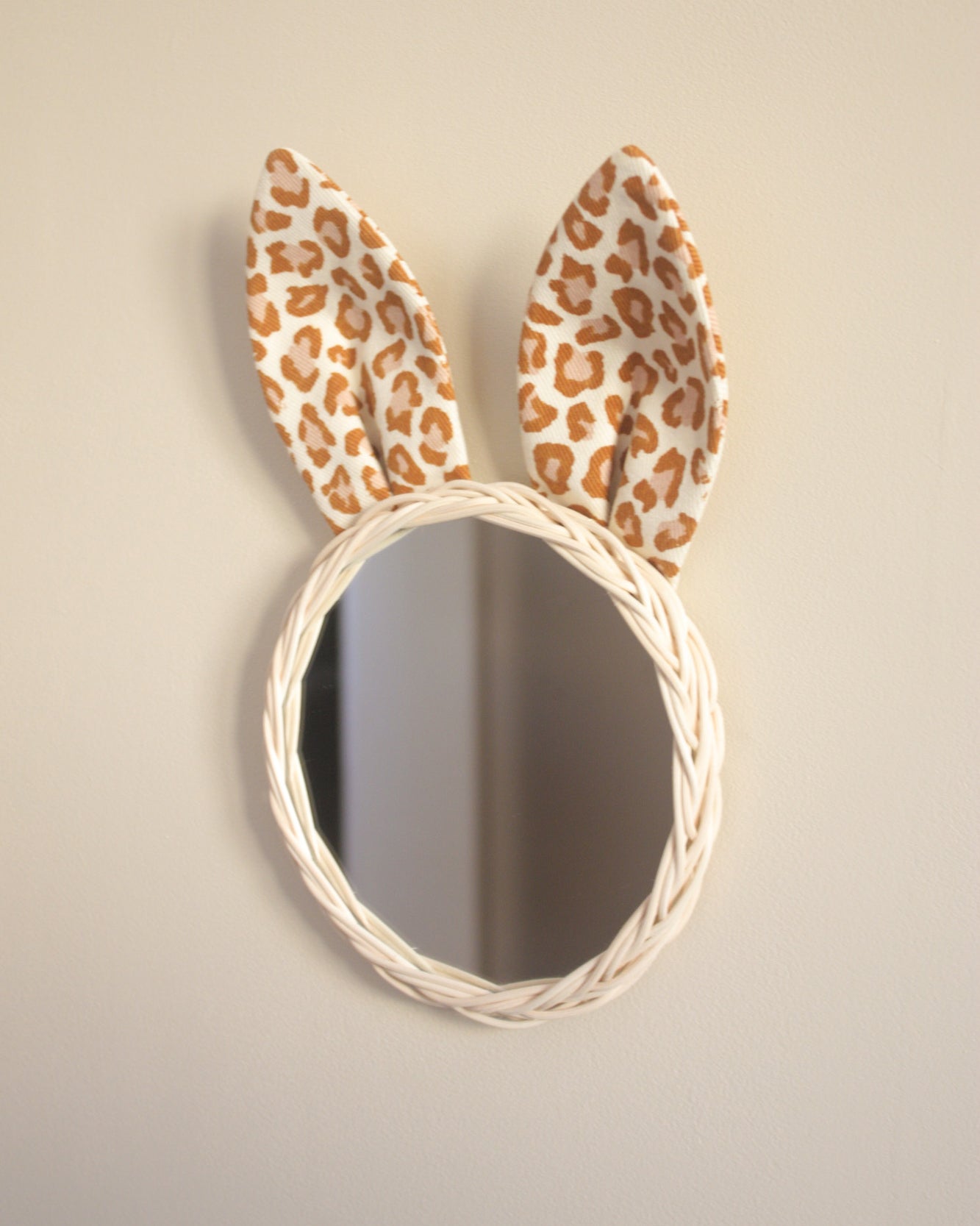 miroir lapin au mur avec un tour en rotin et des oreilles dans une gabardine imprimé léopard